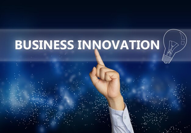 Image du concept d'entreprise d'un homme d'affaires cliquant avec la main sur le bouton Business Innovation sur un écran virtuel