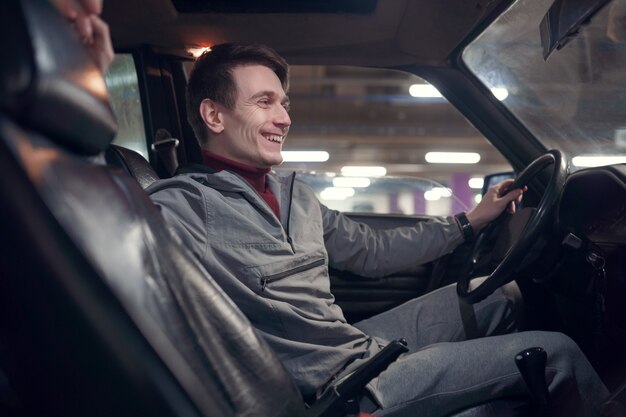 Image du côté du jeune homme souriant assis dans la voiture