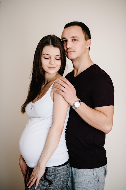 Image du mari debout et tenant le ventre des mains de la femme enceinte Femme fille et bel homme aimant étreindre le ventre à la maison Couple d'amoureux Concept de parentalité Douche de bébé Photo de famille