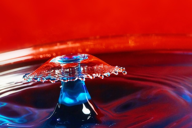 Image de l'eau bleue avec deux gouttes d'eau frappant dans l'air sur fond rouge