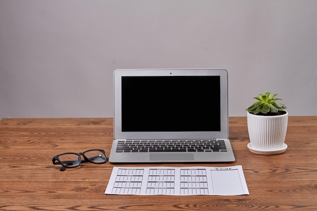 Image d'entreprise du carnet d'horaires avec des lunettes et un écran d'ordinateur portable noir d'ordinateur portable sur un bureau en bois