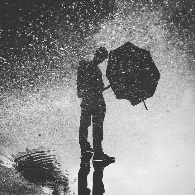 Image à l'envers d'un homme debout avec un reflet dans une flaque d'eau dans la rue