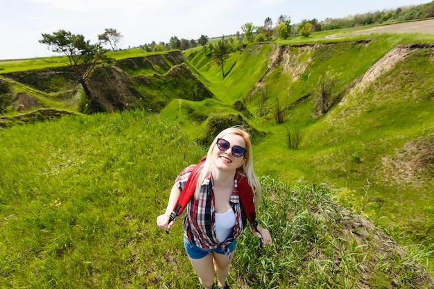 Image d'été de style de vie d'une jolie femme hipster blonde avec sac à dos voyageant et appréciant, look frais et élégant, bonne humeur, couleurs ensoleillées, concept de voyage, émotions.