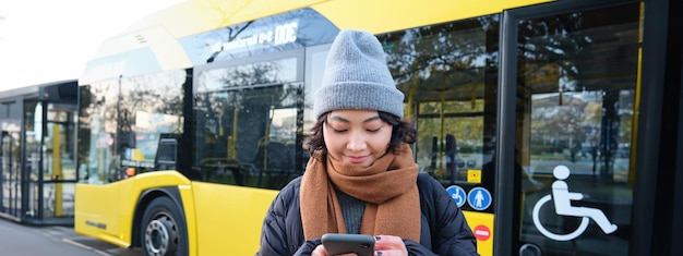 L'image d'une étudiante en attente de l'horaire des contrôles des transports publics sur l'application pour smartphone se trouve à proximité