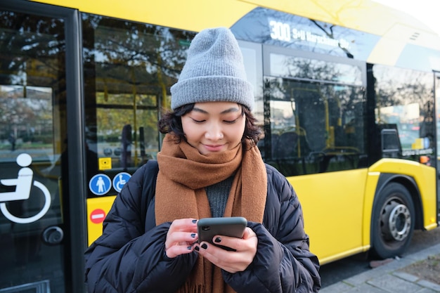 Image d'une étudiante en attente de l'horaire des contrôles des transports publics sur l'application smartphone se trouve près de cit