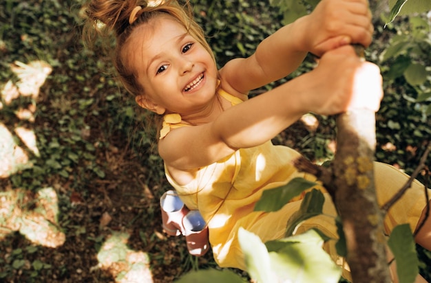 Image à l'extérieur d'une adorable petite fille blonde mignonne jouant et souriant largement au fond de la nature Enfant heureux se balançant sur un arbre en été dans le parc Enfant joyeux s'amuser dans la forêt