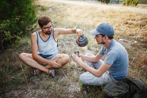 Image à l'extérieur d'un jeune explorateur buvant une boisson chaude dans les montagnes assis et relaxant après une randonnée