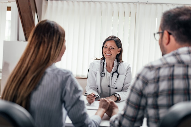 Image de face d&#39;une femme médecin ayant une consultation avec un couple.