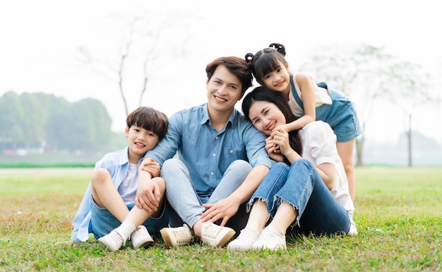 Image d'une famille asiatique assise ensemble sur l'herbe au parc