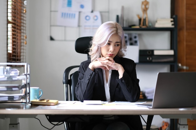 L'image d'une femme d'affaires asiatique stressée s'ennuie et réfléchit trop après avoir travaillé sur une tablette au bureau