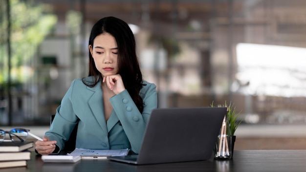 Image d'une femme asiatique fatiguée et qui réfléchit trop après avoir travaillé avec une tablette au bureau.