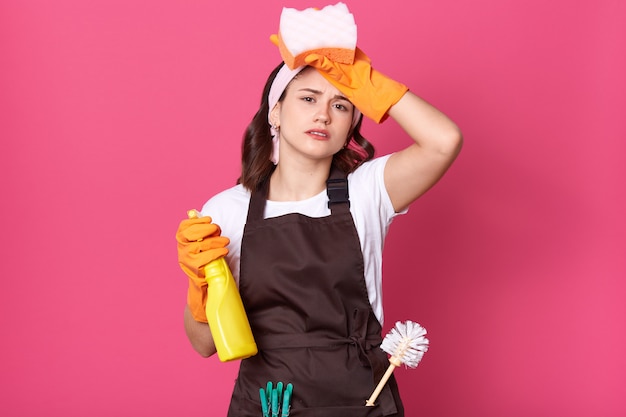 Image de femme au foyer fatiguée bouleversée habille un tablier marron avec un piston et des épingles dans la poche