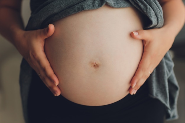 Image de femme enceinte touchant son ventre avec les mains.