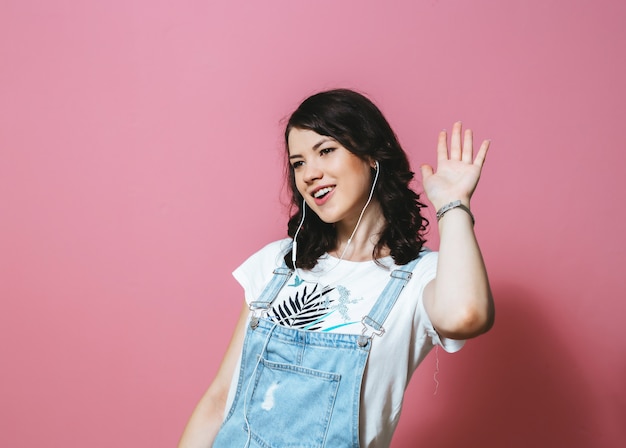 Image de femme heureuse portant des écouteurs chantant isolé sur mur rose