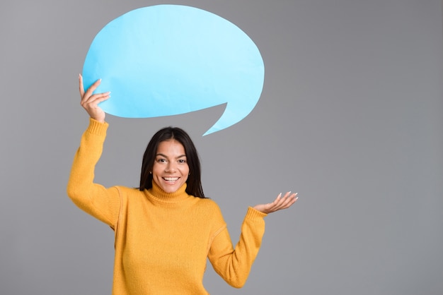 Image d'une femme heureuse posant isolé sur mur gris tenant la bulle de dialogue.