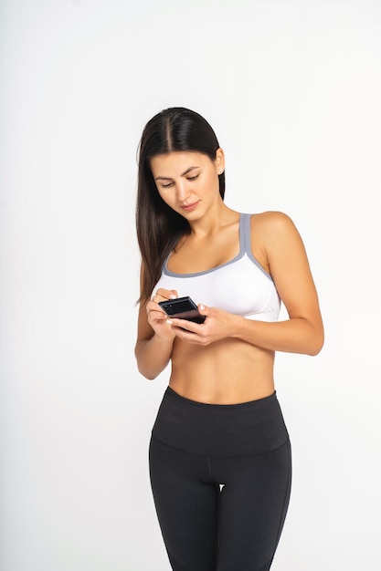 Image d'une femme heureuse souriante et utilisant un téléphone portable isolée sur un mur blanc