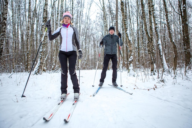 Image d'une femme sportive et d'un homme faisant du ski dans la forêt d'hiver