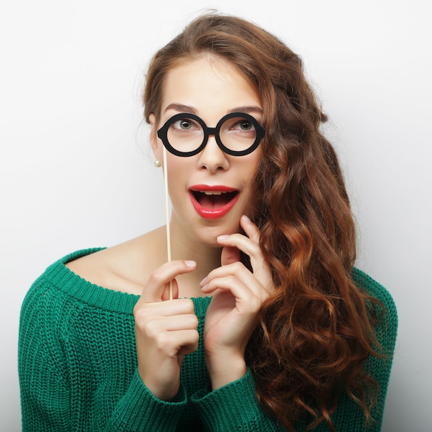 Image de la fête. Espiègles jeunes femmes tenant une lunettes de fête.