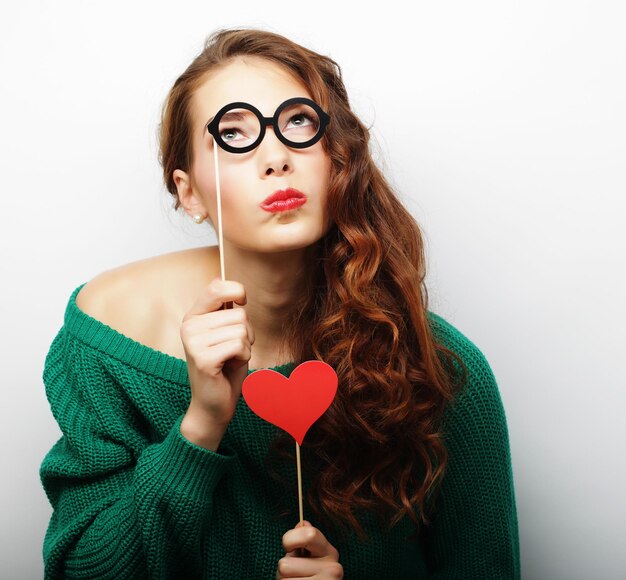 Image de fête Jeune femme espiègle tenant des lunettes de fête