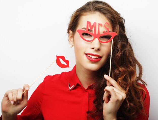 Image de fête. Ludique jeune femme tenant des lunettes de fête.