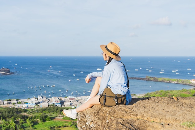 Image d'une fille assise sur une montagne regardant la mer