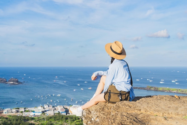 Image d'une fille assise sur une montagne regardant la mer