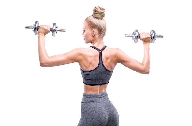 Image d'une fille avec des haltères dans ses mains dans un studio blanc Concept de remise en forme et de musculation Vue arrière