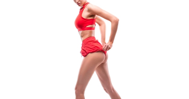 Image d'une fille sportive avec des fesses pompées dans un studio blanc Vêtements de sport rouges Concept de remise en forme et de musculation