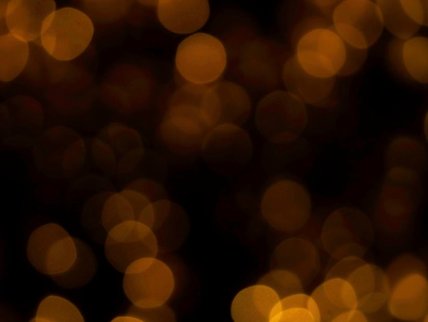 Image floue abstraite de lumière dorée ou jaune de beau bokeh sur fond noir avec espace de copie Fête de nuit festive floue et arrière-plan bokeh de célébration