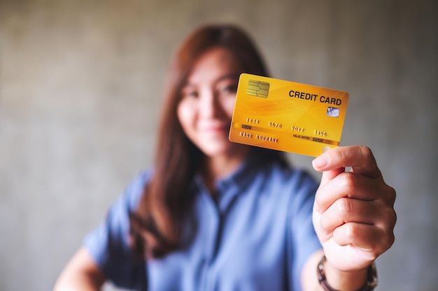 Image floue d'une belle femme asiatique tenant une carte de crédit pour faire du shopping
