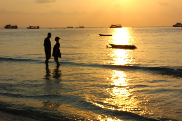 Image floue d'un couple silhouette sur la plage au coucher du soleil, l'amant est célébré le jour de la Saint-Valentin en disant aimer et proposer. L'homme et la femme se marient avant le mariage sur la plage au meilleur moment.