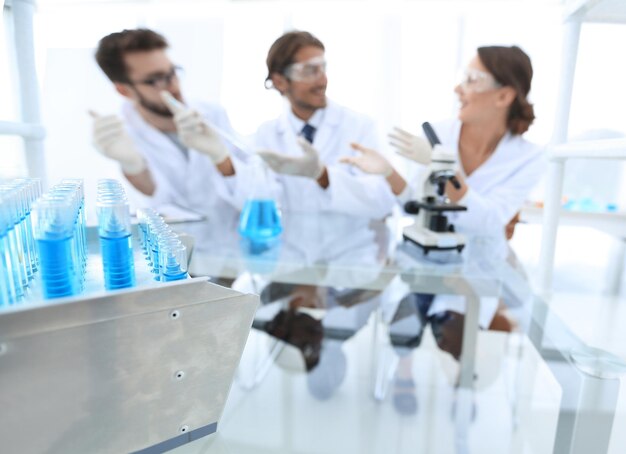 L'image de fond est un groupe de microbiologistes étudiant le liquide dans un tube de verre