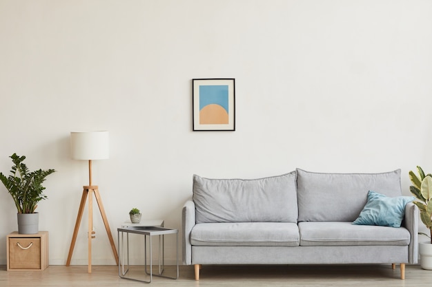 Image de fond d'un intérieur minimaliste avec un accent sur un canapé confortable contre un mur blanc avec de l'art abstrait, espace pour copie