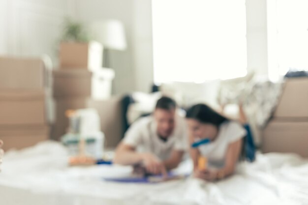 Image de fond d'un jeune couple allongé sur le sol dans un nouvel appartement vide