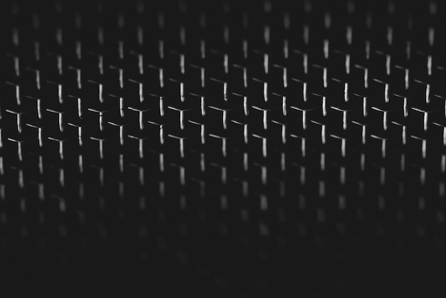 Image de fond de maille brillante sur fond sombre. Texture métallique du gros plan de la grille. Forme triangulaire de la grille. Image abstraite de la surface du haut-parleur audio en macro photographie. Design futuriste.