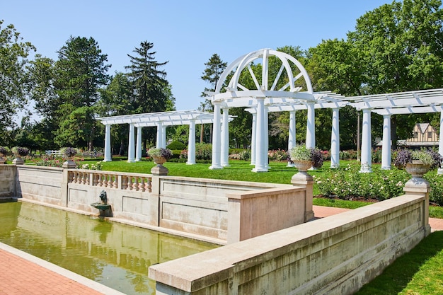 Image d'une fontaine à eau avec tête de lion sur un mur avec pergola herbeuse, parfaite pour les mariages en plein air