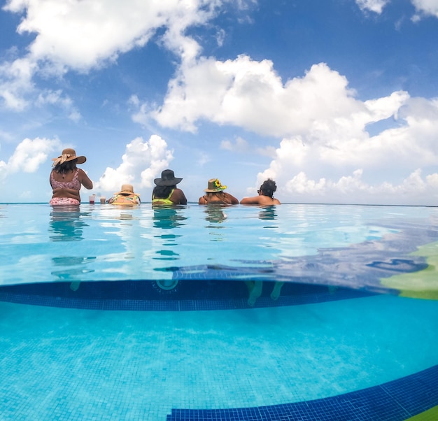 Image fractionnée à moitié sous-marine de jeunes femmes s'amusant dans la piscine de l'hôtel dans le concept de la mer des Caraïbes