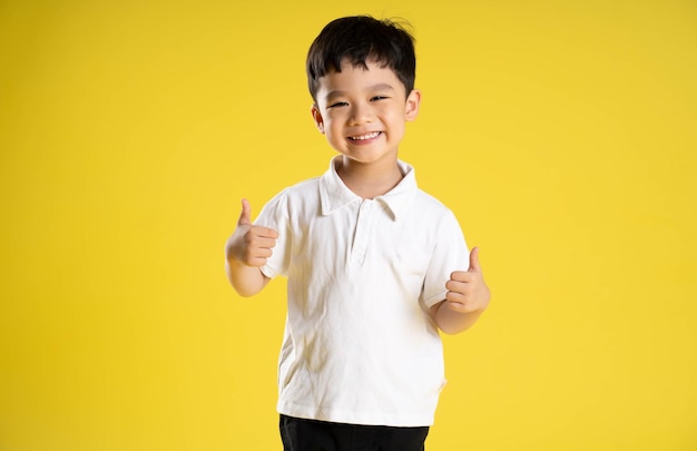 Image d'un garçon asiatique posant sur un fond jaune