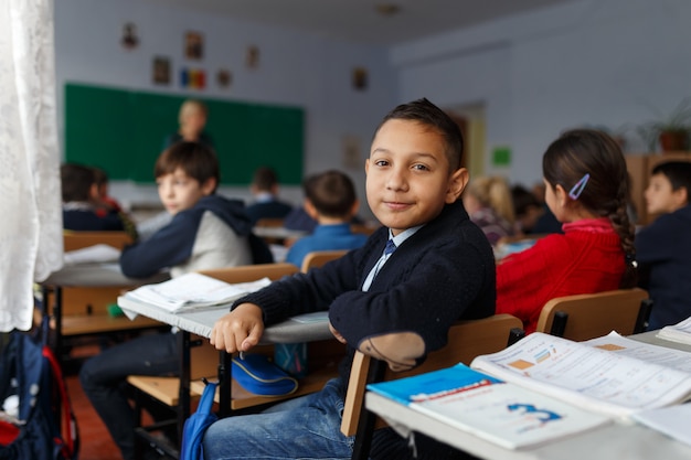 Image avec un garçon assis à sa table à l'école