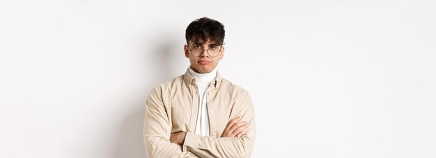 Image d'un gars hipster élégant dans des verres qui s'ennuie à ne pas s'amuser avec les bras croisés de poker sur