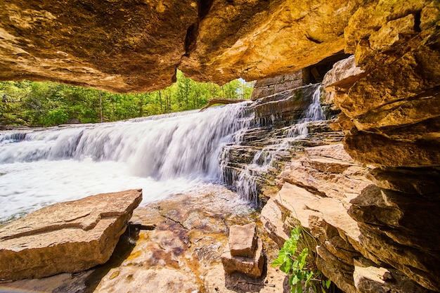 Image de la grande cascade vue de l'intérieur de l'ouverture d'une petite grotte rocheuse