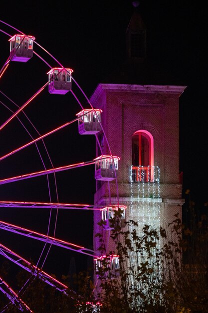 Photo image de la grande roue et d'une tour éclairée pour les fêtes locales