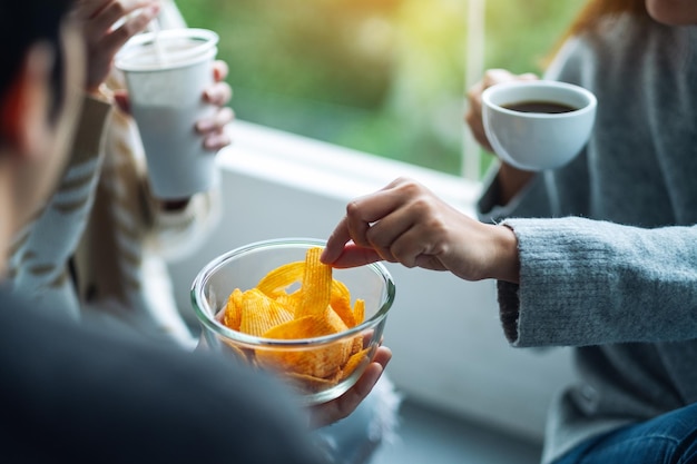 Image en gros plan d'amis buvant et mangeant des croustilles ensemble