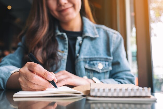 Image en gros plan d'une belle femme asiatique écrivant sur un cahier vierge sur la table