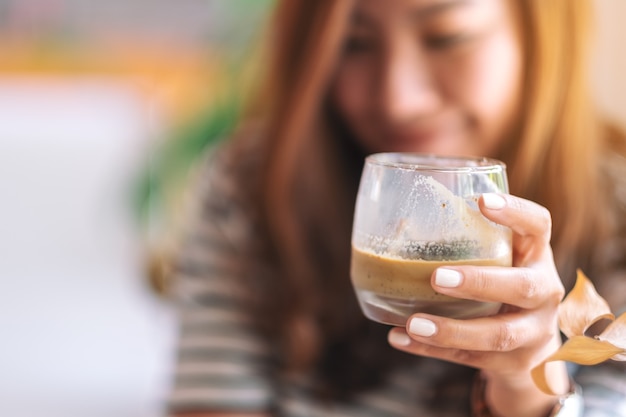 Image Gros plan d'une belle femme tenant un verre de café glacé à boire au café