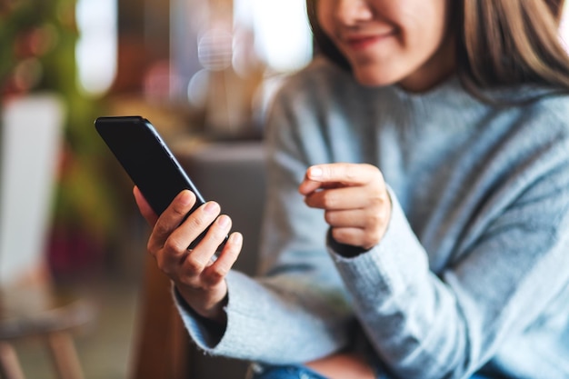 Image en gros plan d'une belle jeune femme asiatique tenant et utilisant un téléphone intelligent