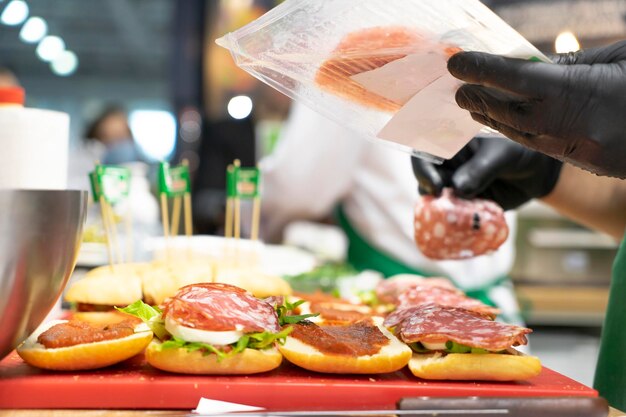 Image en gros plan d'un chef cuisinant un sandwich avec de la viande et des légumes dans la cuisine