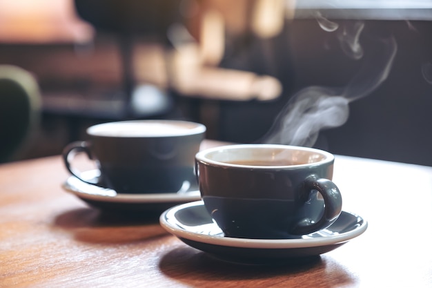 Image Gros plan de deux tasses bleues de café latte chaud et café Americano sur table en bois vintage au café