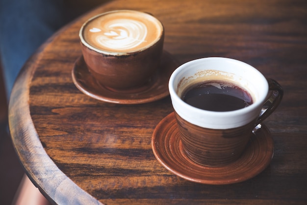 Image Gros plan de deux tasses de café latte chaud et café noir sur une table en bois vintage au café