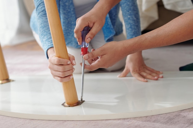 Image gros plan du jeune couple fixant la jambe cassée de la table basse